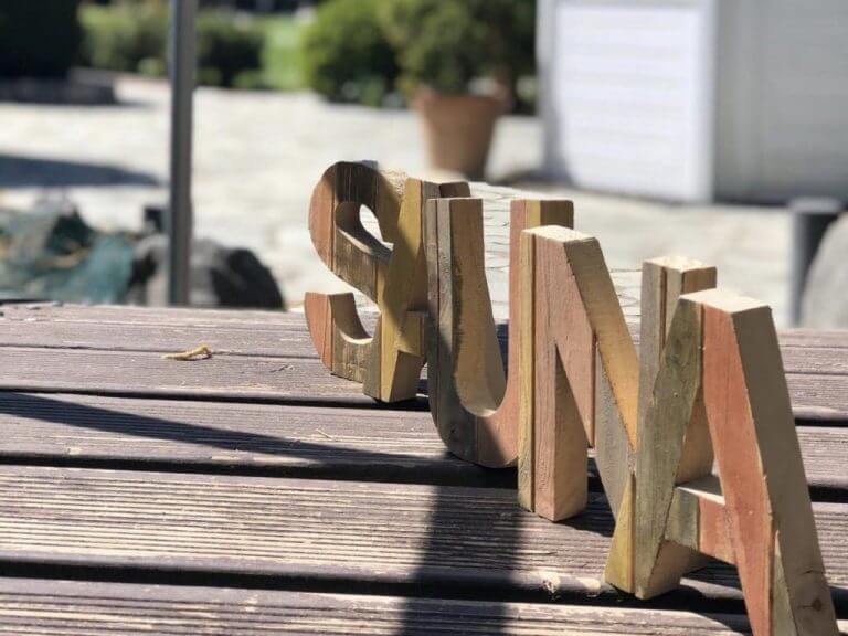 Foto vom Wort Sauna in Holzbuchstaben auf Holztisch